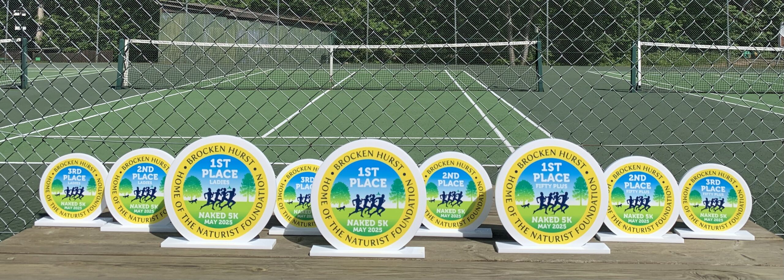 Naked 5k medals on a table by tennis courts at the naturist foundation for nude sports activities and British naturists