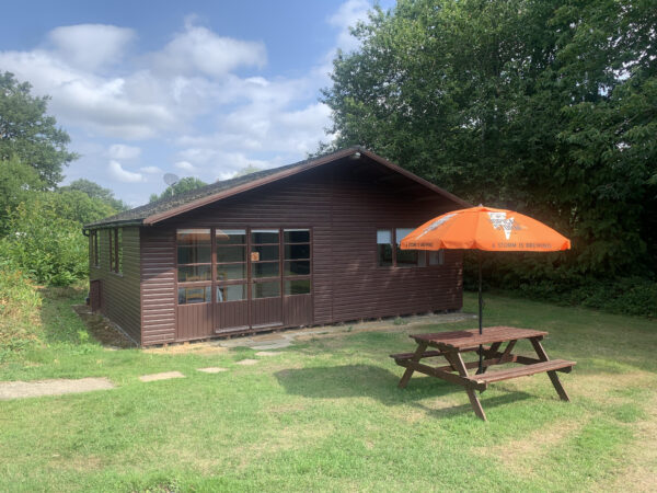Naturist accommodation UK featuring the chalet at Brocken Hurst, a stand alone cabin surrounded by woodlands and grass