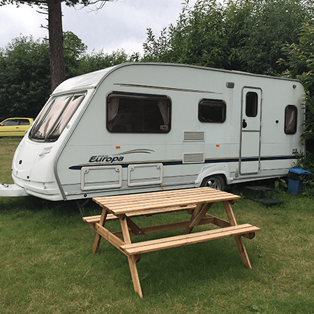 Naturist caravan campsite at Brocken Hurst, home of the naturist foundation featuring a caravan, wooden table, and woodlands